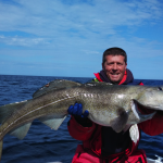 strahlender Angler mit großem Dorsch aus dem Nordmeer